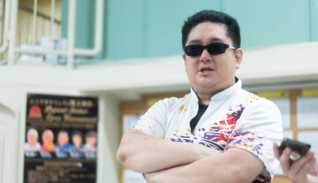 腕組みをして話している、サングラス姿の井上さん。
