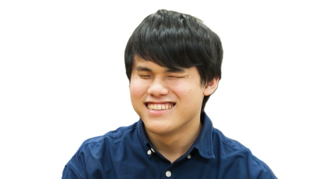 笑顔で話している、青いシャツを着た川本さん