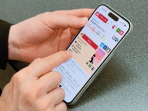 「耳で聴くハザードマップ」のスマートフォン画面を操作している手元のクローズアップ写真。