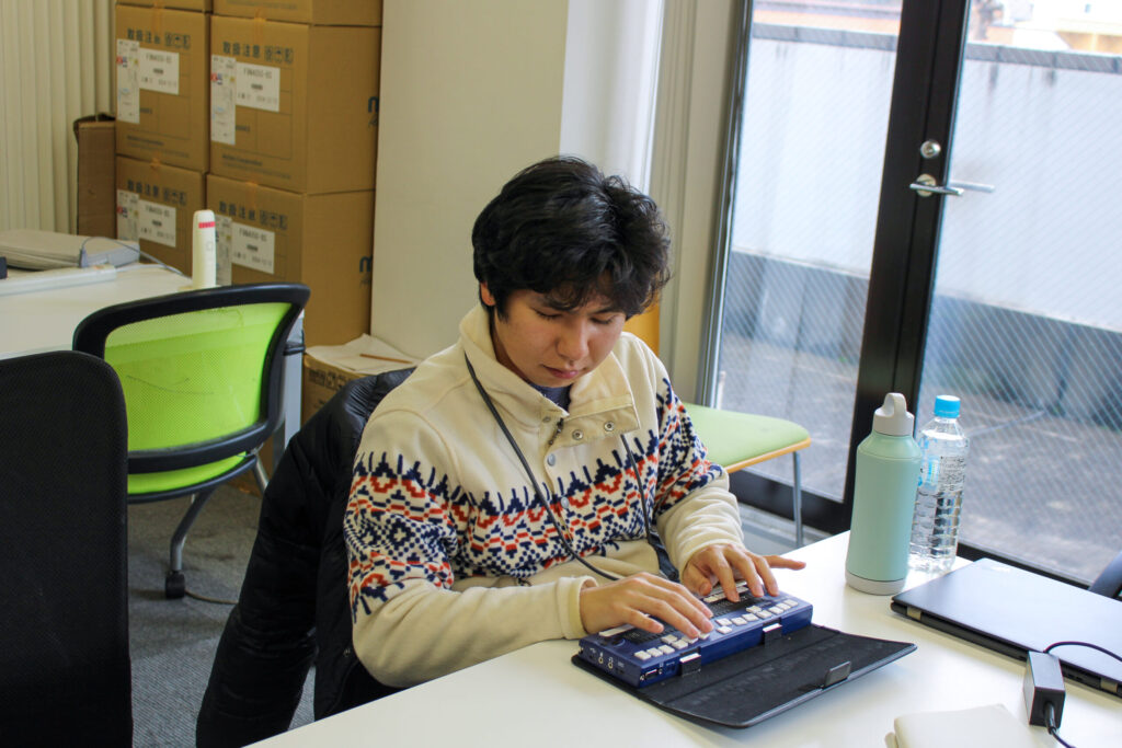 参加者の一人が、真剣な表情で点字ディスプレイを打ち込んでいる様子。