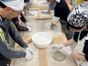 テーブルを囲んで、みんなでそば生地を作っている様子。