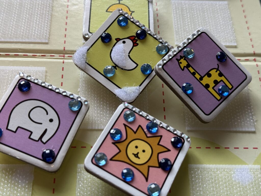 「デコどうぶつしょうぎ」完成品のイメージ写真。ゾウ、ニワトリ、ライオン、キリンのイラストのコマ。それぞれ違った位置にラインストーンがつけられている。