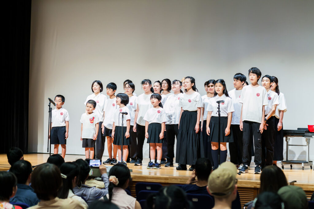 ステージで歌っている「いちご合唱団」の皆さん。上は白い服、下は黒い服で統一している。