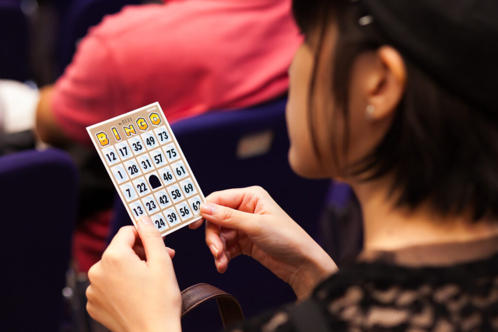 参加者が手に持っているビンゴカードのクローズアップ写真。カードはスタート時点の中央だけ穴をあけてある状態。