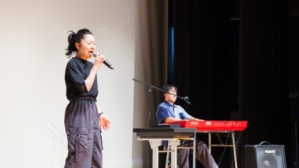 女性ボーカルと男性ピアノ伴奏のユニット。ステージ上で演奏中の様子。
