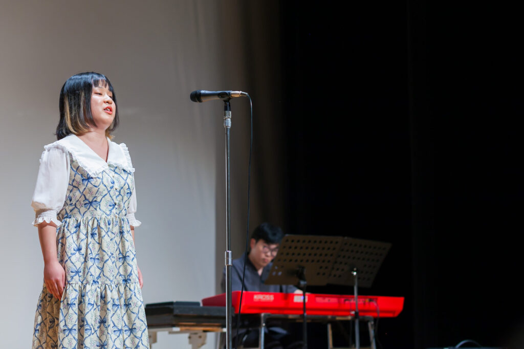ステージ上で歌っているボーカルの女性と電子ピアノで演奏する男性。