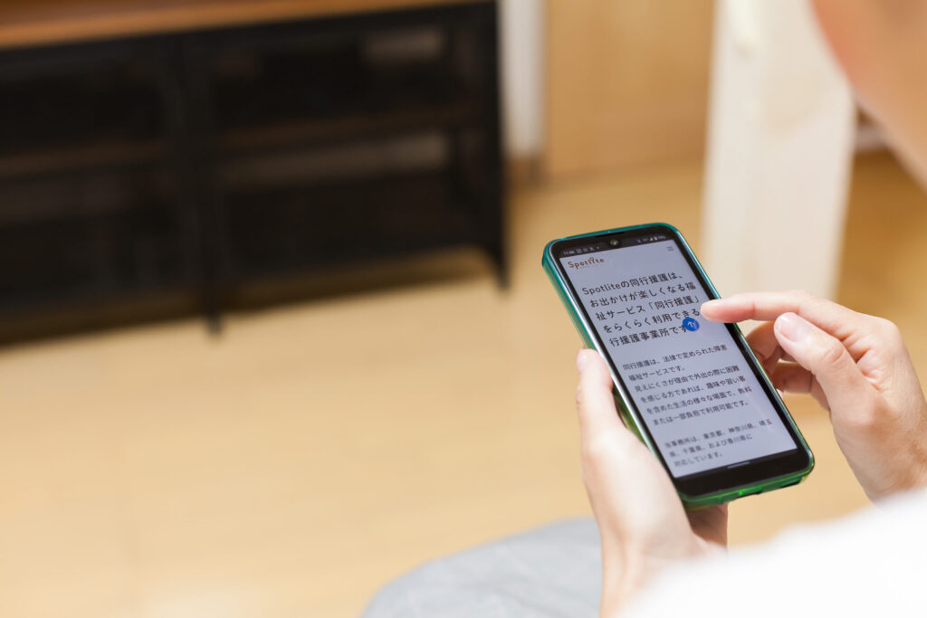 スマートフォンを使用している手元のクローズアップ。音声読み上げ機能でSpotlliteの記事を読んでいるところ。