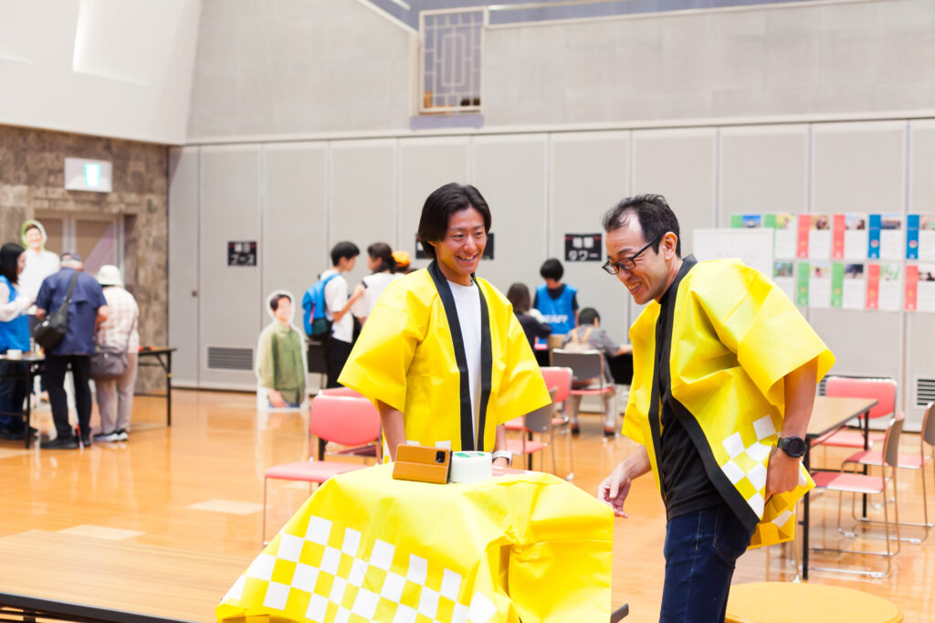 みつきエキスポで、撮影のためのスマートフォンの設置について笑顔で相談するみつきのスタッフ。