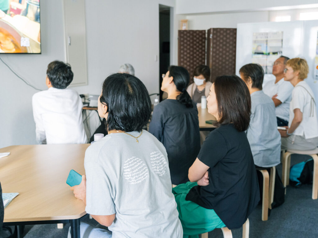 身を乗り出して熱心な様子で講義を聞く参加者。写真には8人写っている。