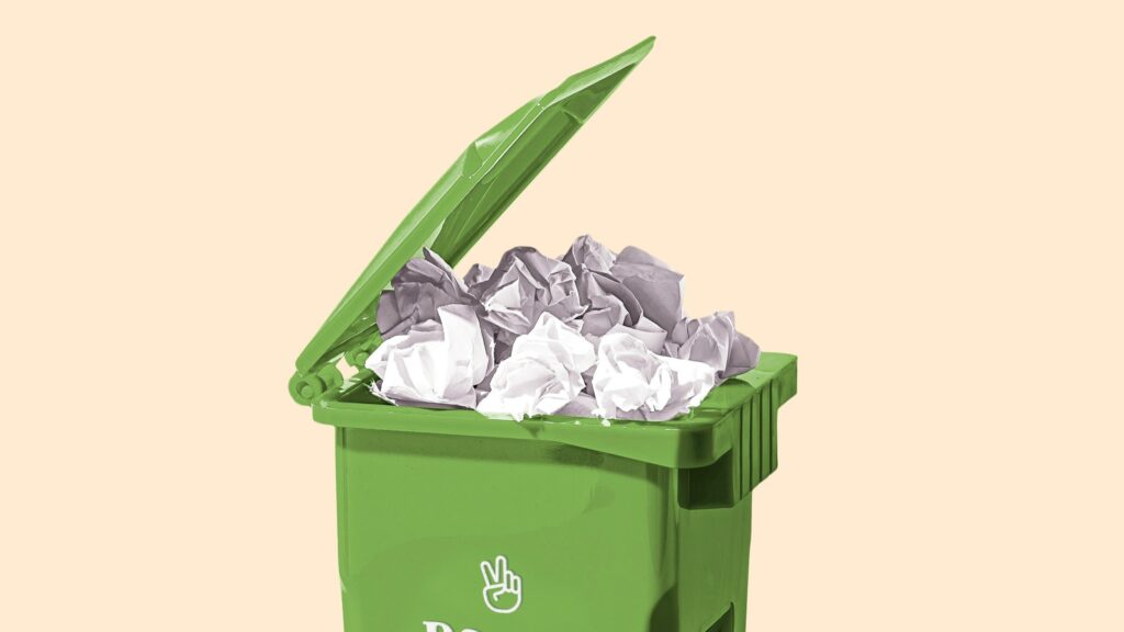 緑色の四角い蓋つきゴミ箱のフタが開いていて、丸めた紙ごみがあふれそうなくらい詰まっている。