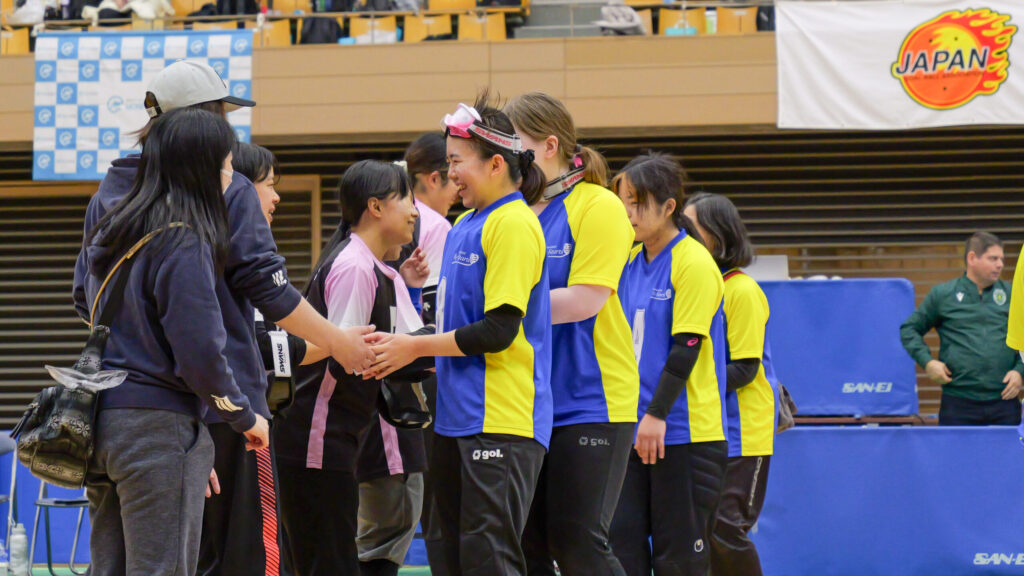 試合後、一列に並んで順番に握手する対戦チームの選手たちとコーチ陣。