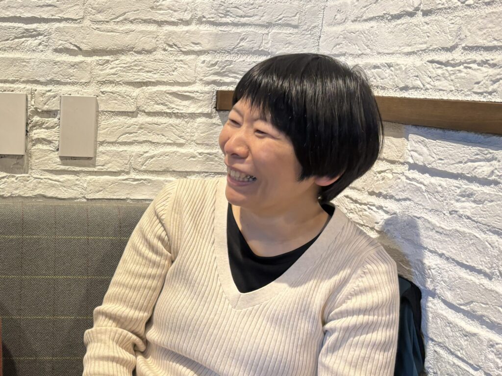 満面の笑顔で話している白い服を着た栗原さん。