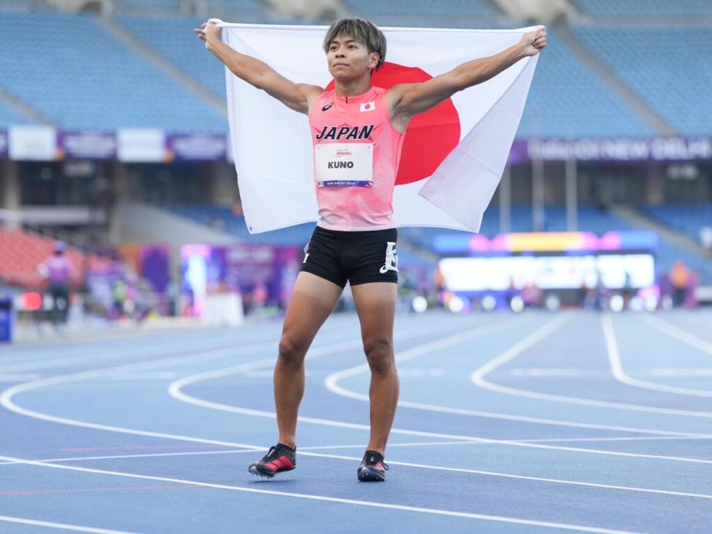 久野選手がニューデリー世界パラ選手権で2位になった直後の様子。日本国旗を両手で自分の背中側に広げて持っている。