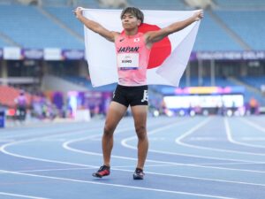 久野選手がニューデリー世界パラ選手権で2位になった直後の様子。日本国旗を両手で自分の背中側に広げて持っている。