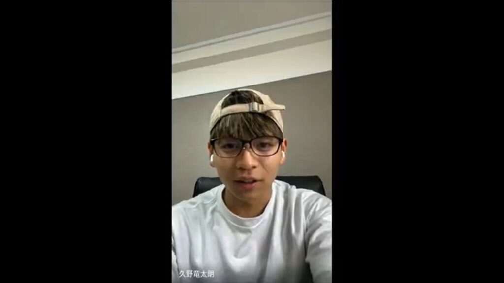 オンライン取材中の久野選手。眼鏡をかけていて白いTシャツ姿でアイボリーのキャップを唾を後ろにしてかぶっている。