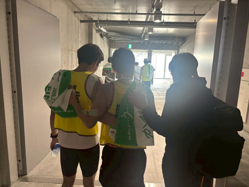 三國さんと肩を組む、伴走の都築さんと加藤さんの後姿。