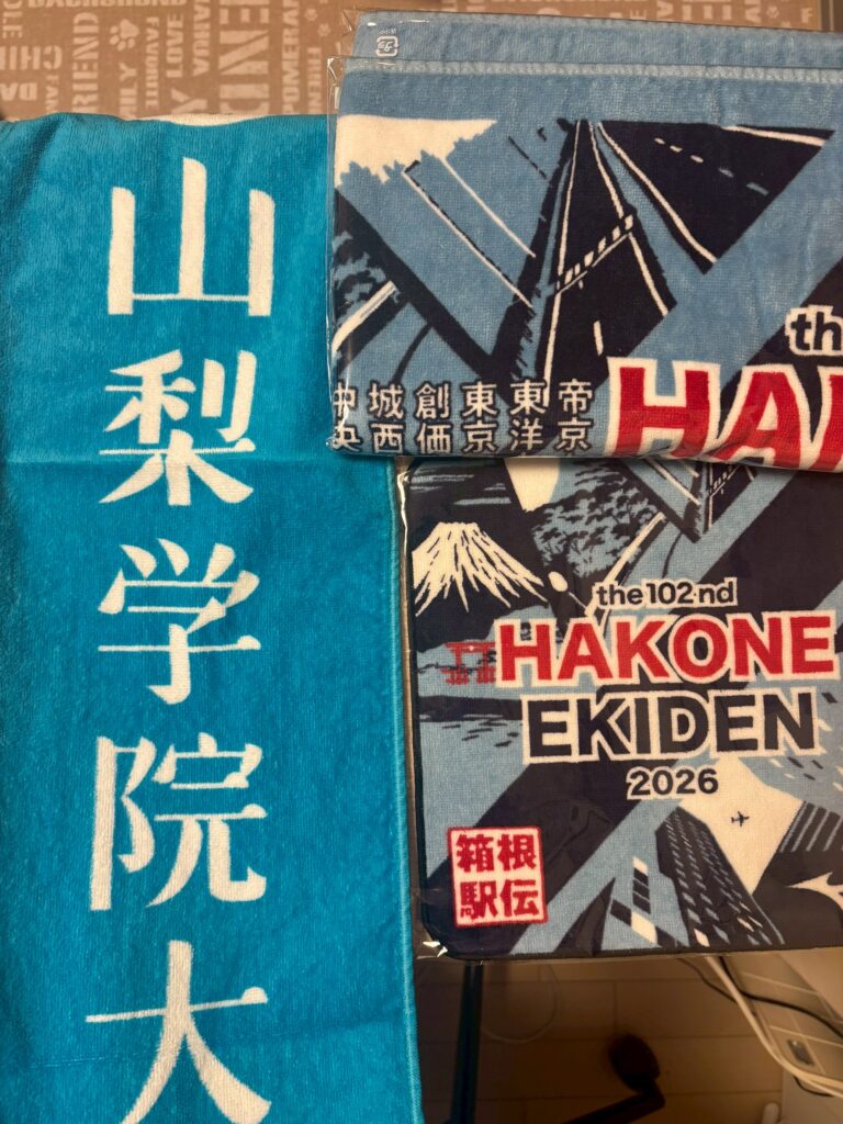「山梨学院大」と書かれた水色のタオルと、「箱根駅伝2026」のタオル。