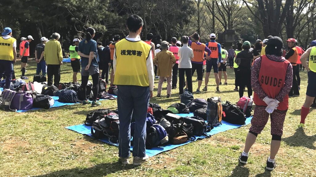 芝生の上で、ガイドランナーについての説明を聞いている参加者。