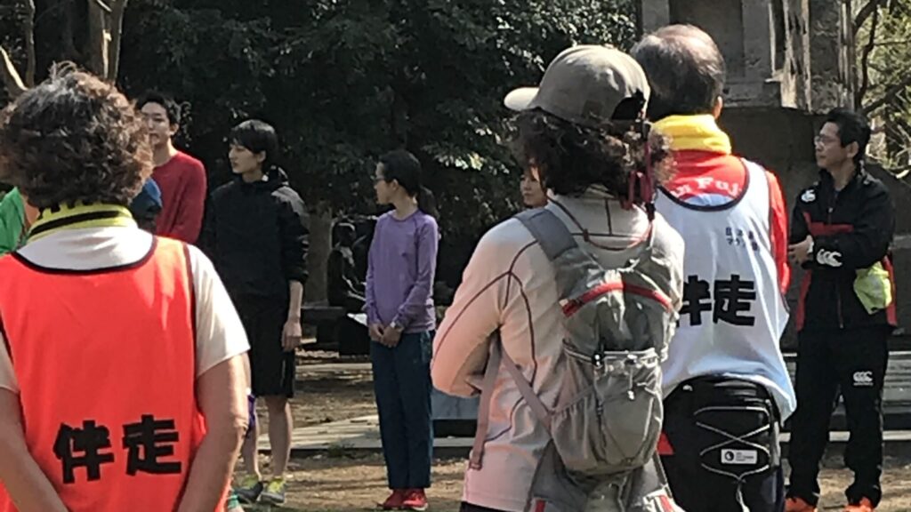 公園内の広場で、輪になってガイドランナーについての説明を聞く参加者たち。