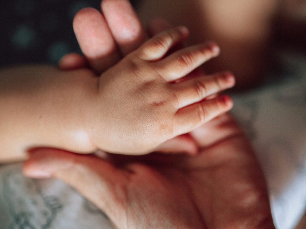 大人の左手の上に、赤ちゃんの左手が重ねられている写真。