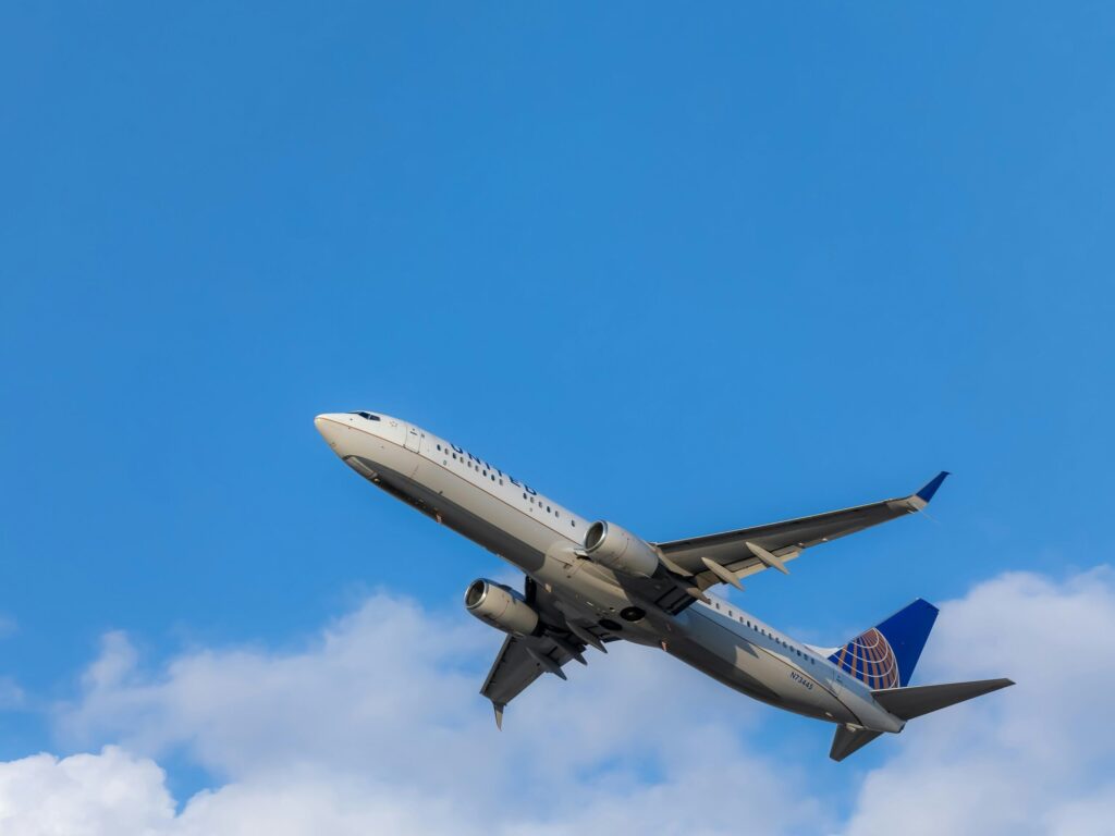 青空を、画面右下から左上に向かって上昇しているジャンボジェット機の写真。