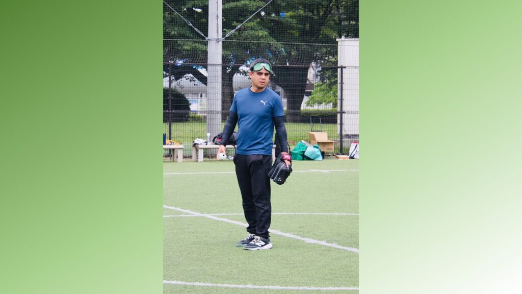 視覚障害者の男性が、グローブを左手に着け、右手でボールを持ち集中している様子。