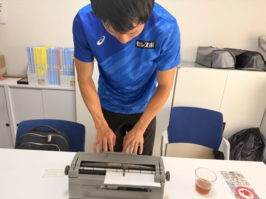 机に置かれた点字タイプライターを実際に使ってみる福永選手。
