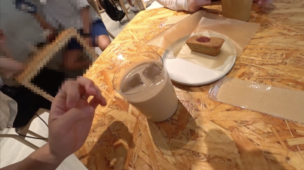 木目調のテーブルに、グラスに入ったアイスカフェラテのようなドリンクと、小さめなマドレーヌのような焼き菓子が乗っている。