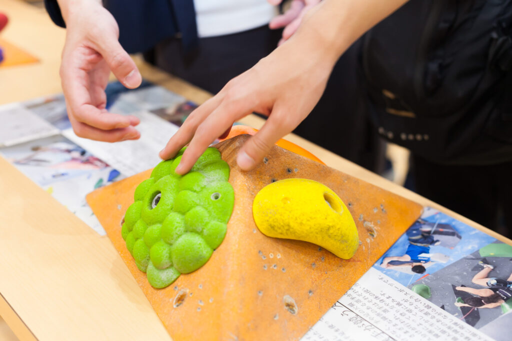 クライミングの際手をかけるホールドのサンプル。参加者が指先で触れている。