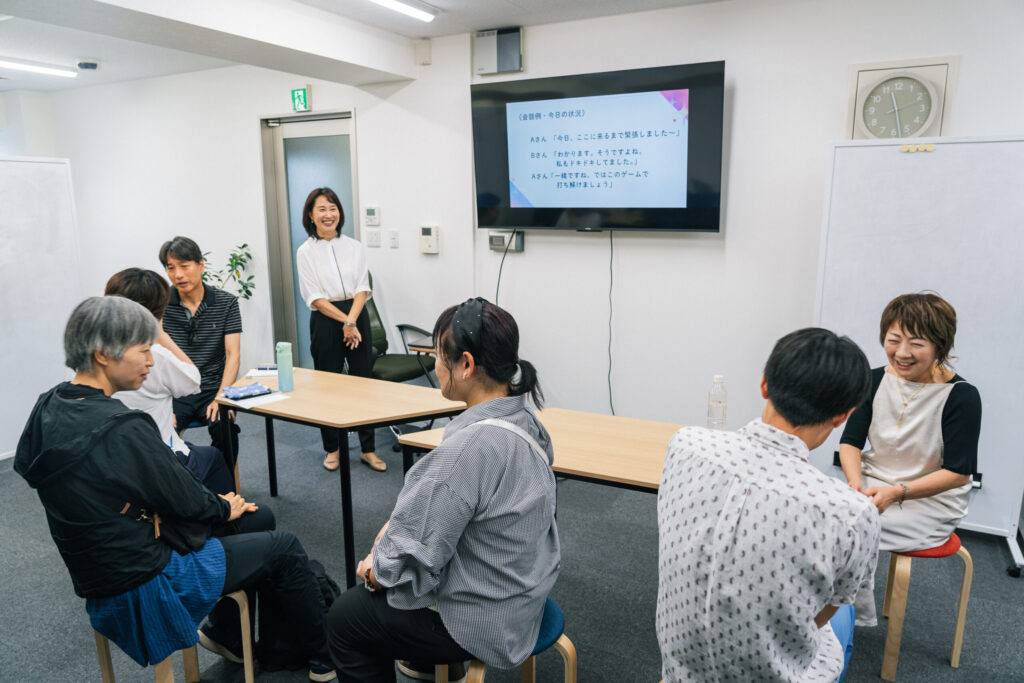 参加者が二人一組で話している様子を、講師の内田さんが笑顔で見守っている。