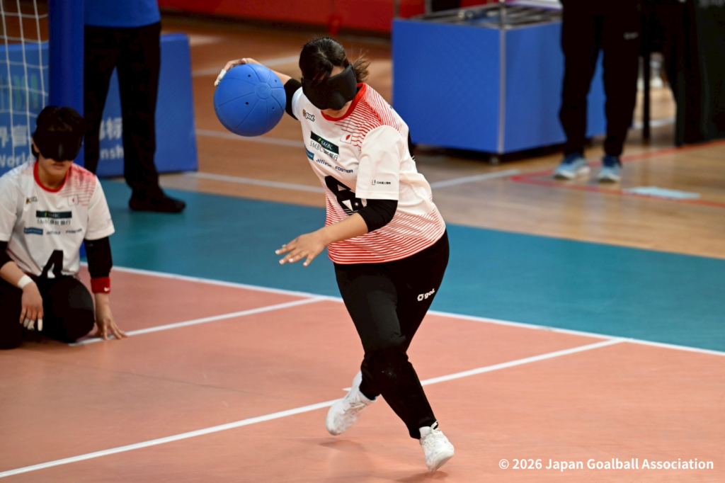 女子オリオンJAPANの競技中の様子。攻撃の選手がボールを持った右手を大きく引いて左足を蹴りながら投球する瞬間。